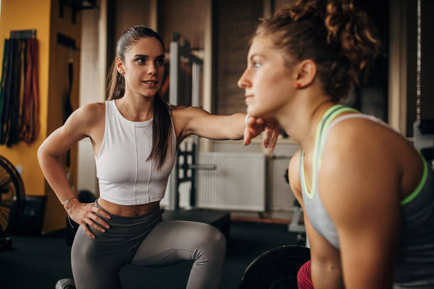istock Personal trainer assisting a young woman in weightlifting 1346331010