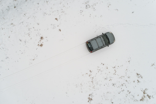 The car is parked in a snowy field. Aerial photography.