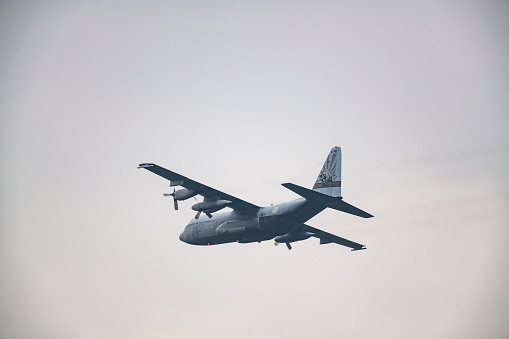 Lockheed C-130 Hercules of the Royal Netherlands Air Force flying in mid air during sunset near Deelen airflield at the Veluwezoom nature reserve in Gelderland, The Netherlands.