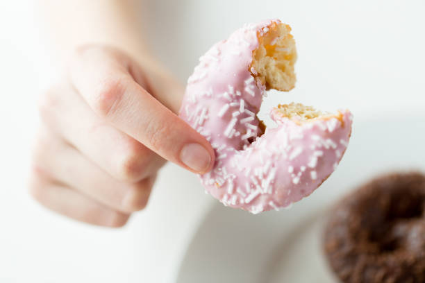 istock close up of hand holding bitten glazed donut 1346333783