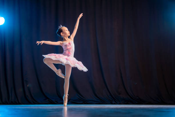 ein kleines mädchen ballerina tanzt auf der bühne in einem weißen tutu auf spitzenschuhen eine klassische variante. - balletttänzer stock-fotos und bilder
