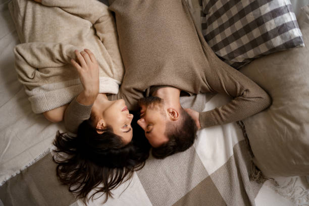 casal lindo deitado na cama relaxando juntos - women heterosexual couple love men - fotografias e filmes do acervo