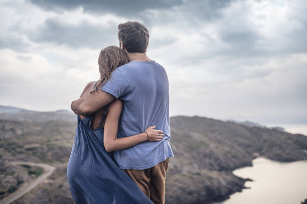 Rear view of a bonding heterosexual couple under dramatic sky