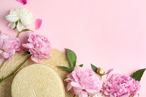 Bouquet of beautiful peonies with straw hat on pink background, flat lay. Space for text