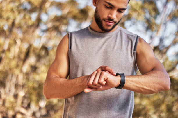 istock Shot of a handsome young man standing alone and setting a timer on his watch before running outside 1346339587