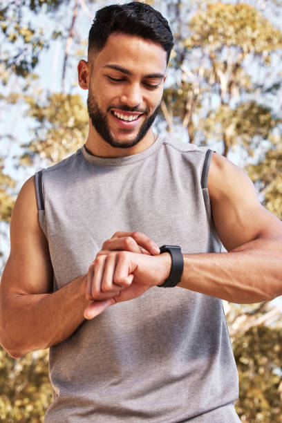 istock Shot of a handsome young man standing alone and setting a timer on his watch before running outside 1346339601