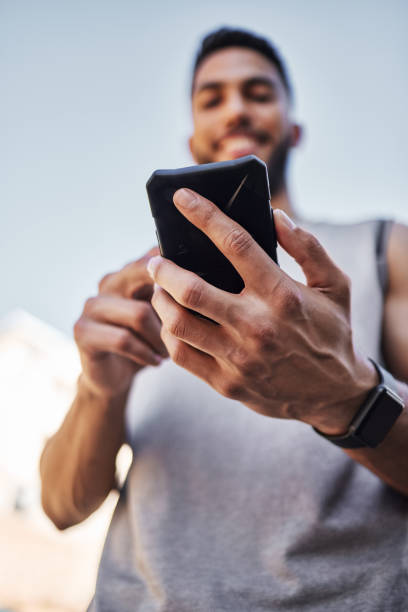 istock Shot of a young man standing alone outside and using his cellphone during his run 1346339608