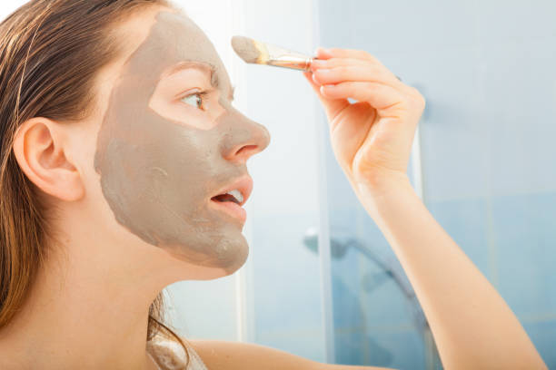 istock Woman applying mud facial mask 1346343023