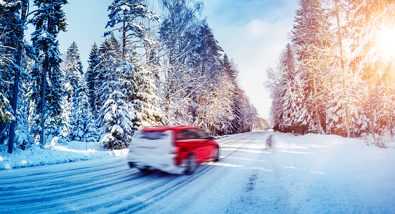 Beautiful snowy country road in winter with cars on it. Concept of the family trip and vacation.