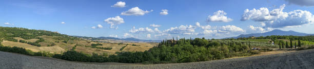 Tuscany, Italy. August 2020. Amazing landscape of the Tuscan countryside with the typical rolling hills and cypresses to mark the boundaries. Large panoramic format of the photo.