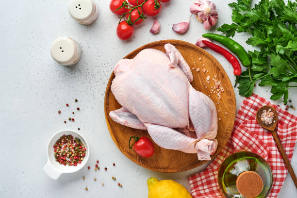 istock Whole raw chicken with ingredients for making rose pepper, lemon, thyme, garlic, cherry tomato sorrel and salt in the kitchen on light grey slate, stone or concrete background Top view with copy space 1346343870