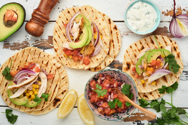 istock Mexican tacos with grilled chicken, avocado, corn kernels, tomato, onion, cilantro and salsa old white wooden table. Traditional Mexican and Latin american street food. Top view. 1346344069
