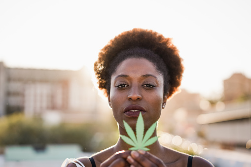 Young african girl holding marijuana leaf - Focus on woman face