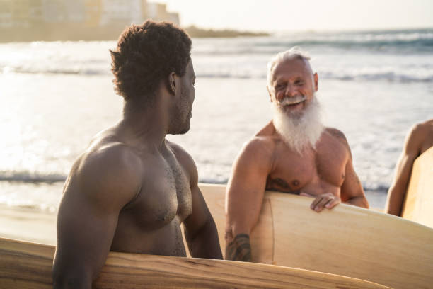 istock Multi generational surfer men having fun on the beach - Focus on african man 1346346692