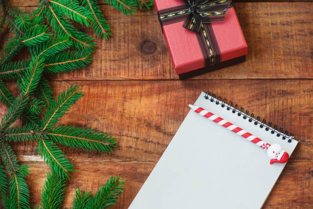 istock Christmas background. Spruce branches in the form of a round frame, gift and notebook with pen on a wooden background 1346346762