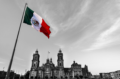Mexico City Cathedral with Mexican Flag, view from below blue sky background,partial black and white