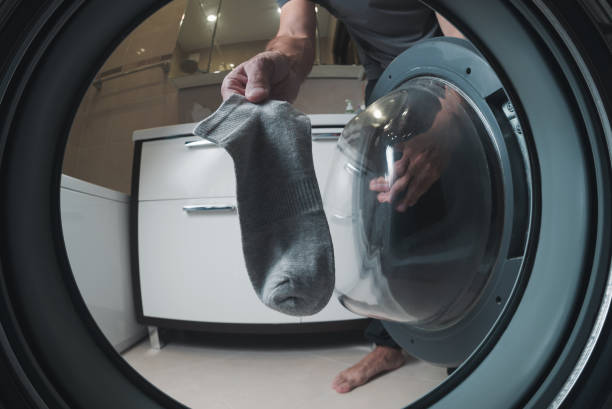 The man puts a sock in the washing machine