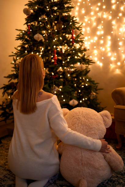 istock Woman hugging bear looking at Christmas tree 1346348236