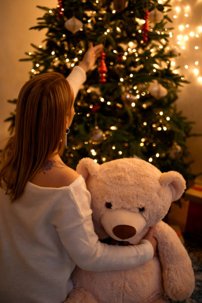 Woman hugging bear looking at Christmas tree