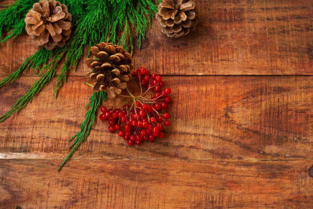 istock Christmas background. Spruce branches, red berries, pinecones on a wooden background. Copy space 1346348314
