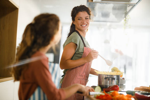 istock Happy mother and daughter talking while making lunch in the kitchen. 1346348319