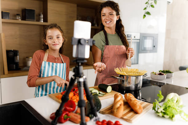 istock Happy mother and daughter having a live broadcast while preparing lunch in the kitchen. 1346348337