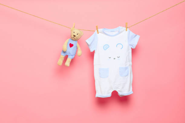 Baby clothes on a clothesline on pink background - Image