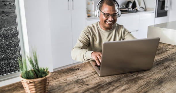 istock Senior african man using laptop computer while wearing headphones at home - Focus on face 1346349562