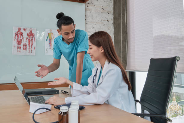 Two uniformed young doctors work in medical clinic office.
