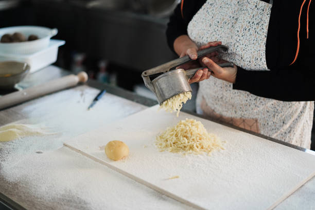 istock Woman using potato press for fresh hand made gnocchi inside pasta factory 1346349722