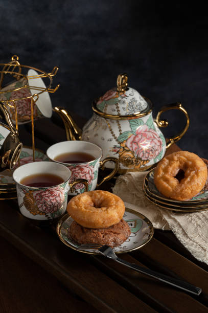 afternoon tea image with black tea,donuts and beautiful teapot and cup on board - brownie tea afternoon tea scone imagens e fotografias de stock