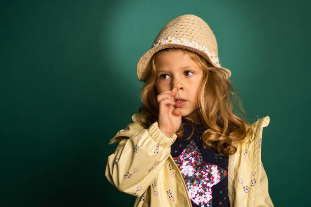 portrait d’une drôle de petite fille mignonne sur fond vert avec un chapeau qui cueille le nez - poking nose in photos et images de collection