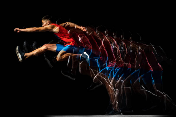 retrato de cuerpo entero de un joven, atleta profesional de pista, corredor en un salto, entrenando aislado sobre fondo negro. efecto estroboscopio. - stroboscopic image fotografías e imágenes de stock