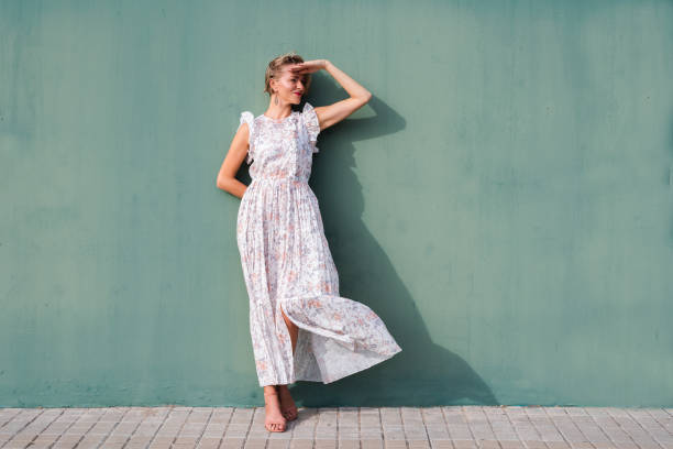 retrato horizontal de una hermosa mujer rubia protegiendo sus ojos con la mano en un día soleado - floral dress fotografías e imágenes de stock