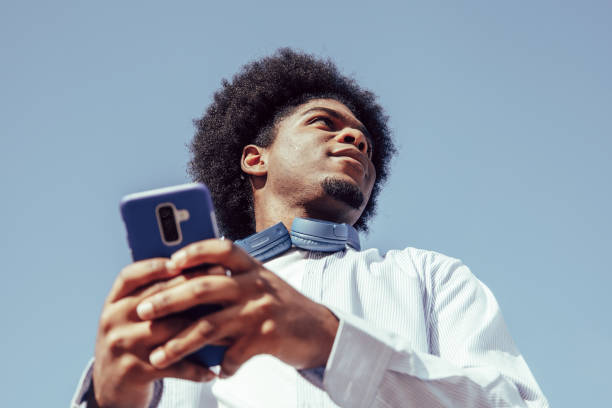スマートフォンを使った若いアフリカ系アメリカ人男性の下からの眺め - 真下からの眺め ストックフォトと画像