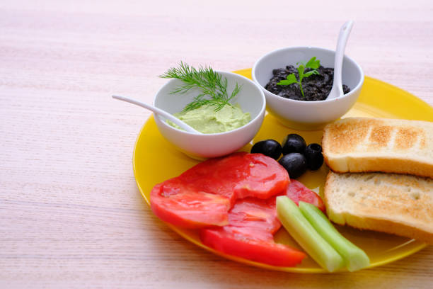 A vibrant arrangement of guacamole, salsa, and creamy dip on a round wooden platter, accompanied by lime wedges, creating a fresh and appetizing scene.