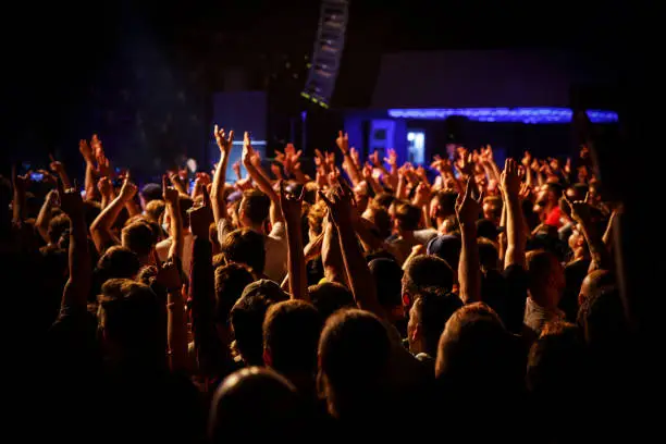 Photo of People at a public event. Crowd with raised hands at a concert.