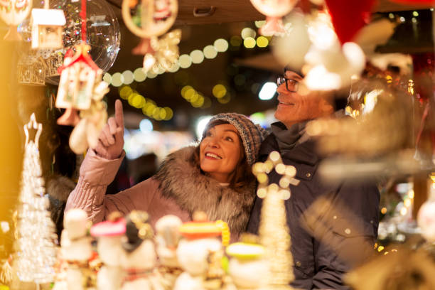 seniorenpaar im weihnachtsmarkt souvenirladen - christkindlmarkt stock-fotos und bilder