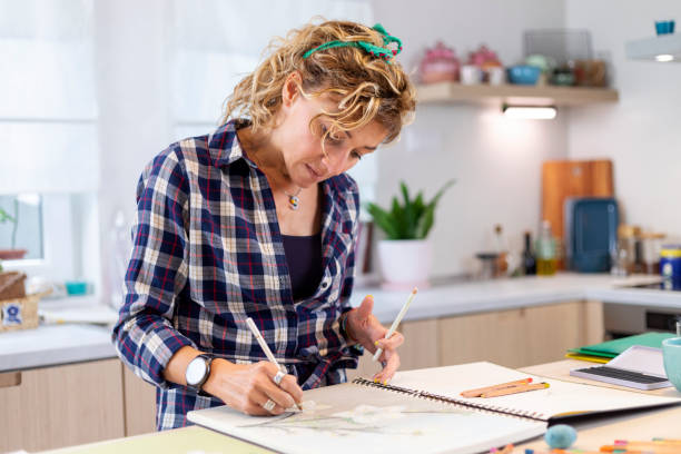 istock Attractive woman doing a drawing with a pencil in the notebook 1346365294