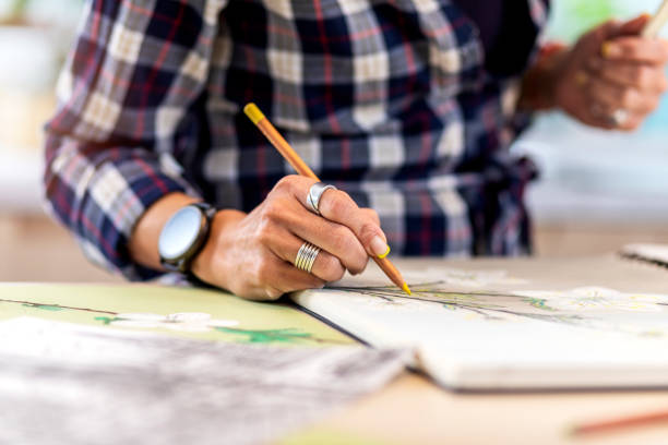 istock Close-up of a woman's hand holding a pencil and drawing on a notebook 1346365338