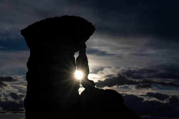 The full moon shines through a gap in silhouetted hoodoos stock photo