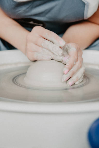白い粘土の瓶や花瓶をクローズアップする。粘土水差しを作る女性の手 ストックフォト