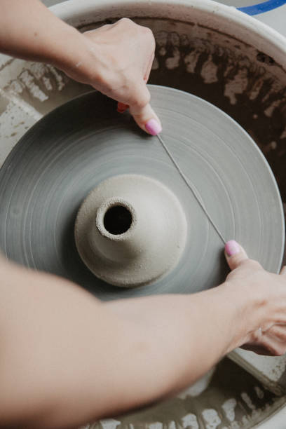 陶芸家のワイヤーで粘土の花瓶を切る女性の手 ストックフォト