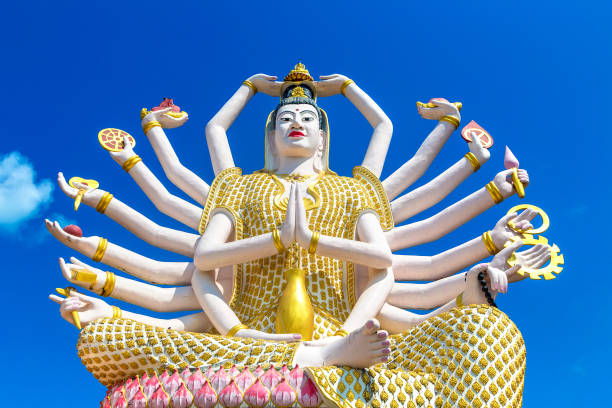 Bronze thai buddha statue in front of tree of life carving agt wall in a white rural thai mountain area temple in Chiang Mai province