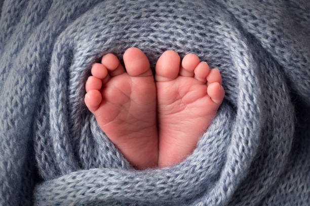 istock Baby's feet in a soft light blue woolen blanket. Small toes. 1346370183