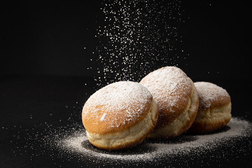 Three donuts filled with marmelade sprinkled with powdered sugar
