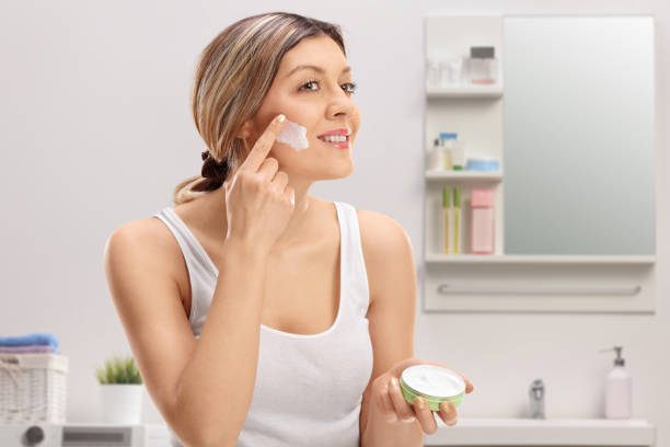 istock Young woman applying face cream inside a bathroom 1346372498