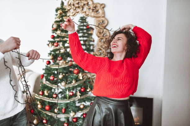 istock Cure Couple Enjoying Decorating Christmas Tree At Home And Playing With Lights 1346372506