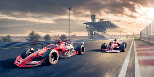 Dos coches de carreras rojos que se mueven a gran velocidad a lo largo de la pista de carreras al atardecer photo