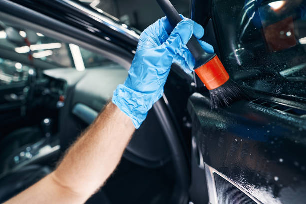 istock Male spreading cleaning detergent on car window with brush 1346375778